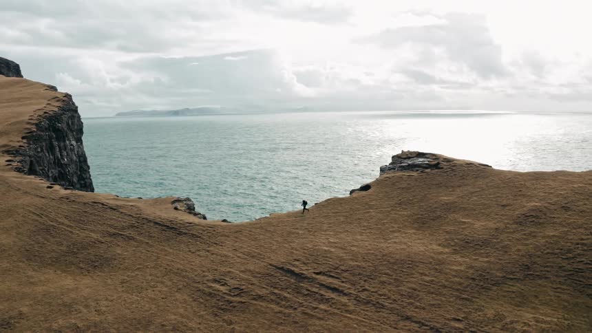 A person running alongside a cliff with its base in the ocean