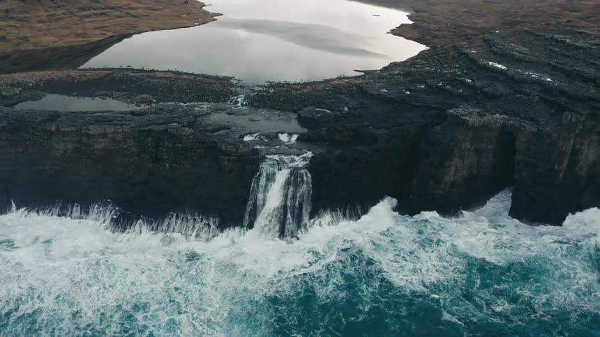 A river cascading over a cliff onto the sea