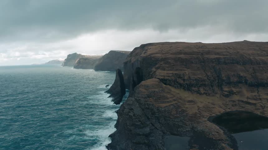 Aerial panorama of the coastal promontory with cliffs by the sea on a cloudy day