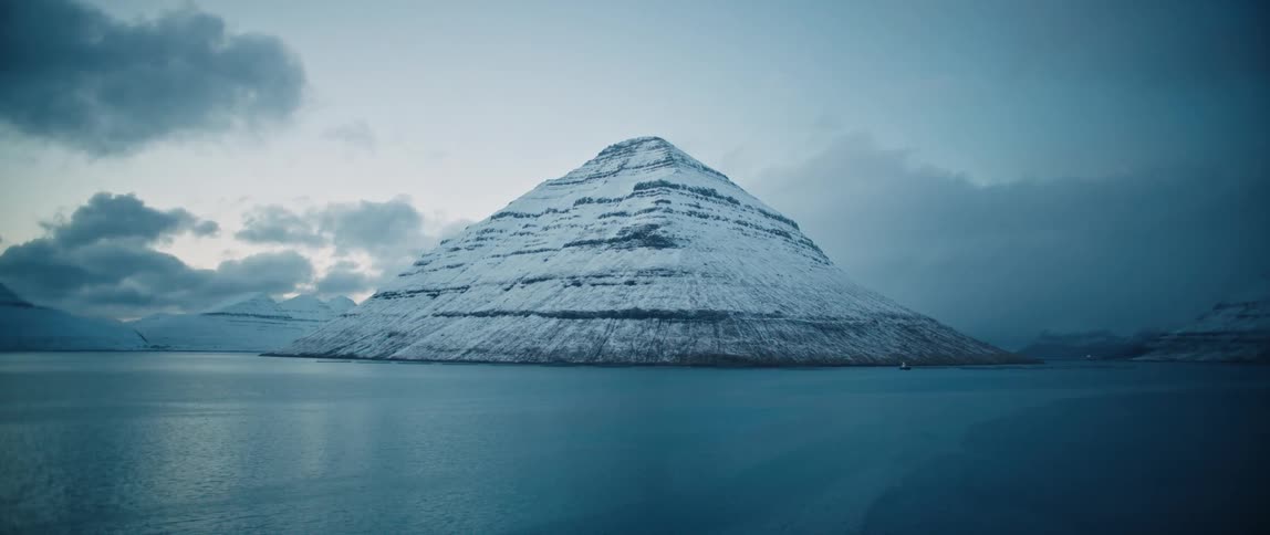 Imposing mountain covered in snow in the coast at evening