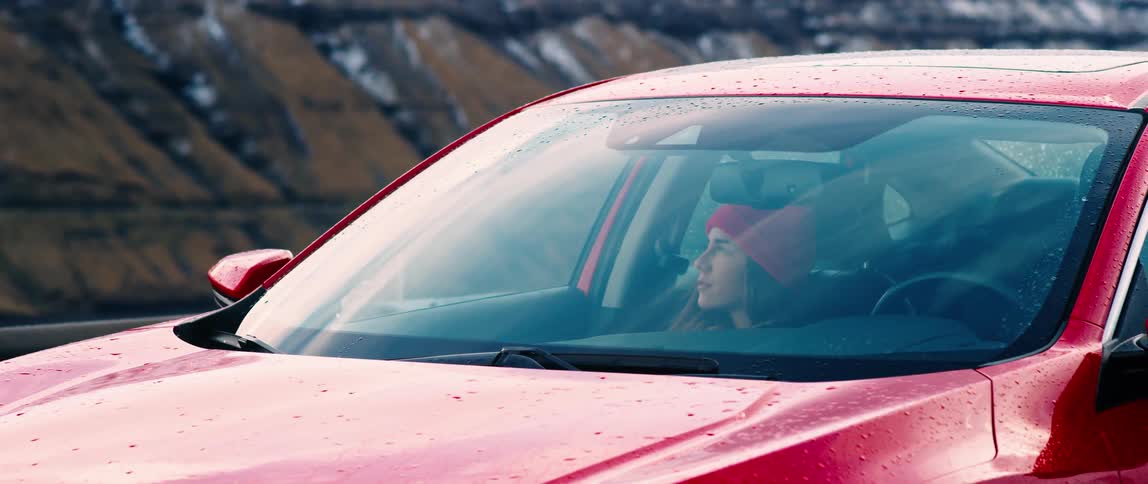 Woman waiting inside a red car in the countryside
