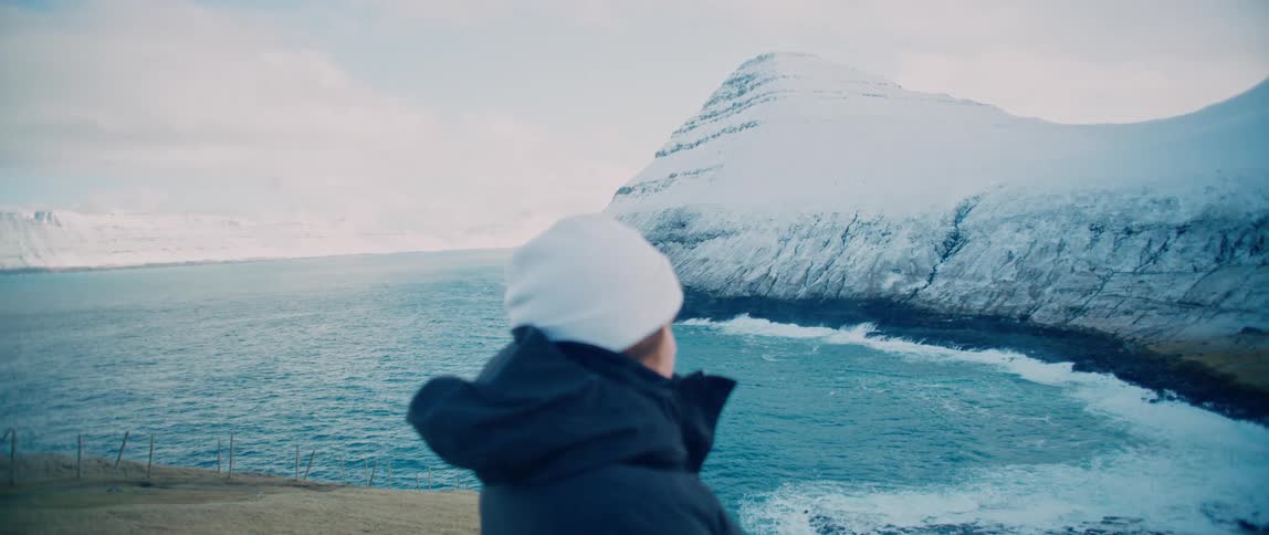 Portrait of a woman facing the sea and the snowcovered village on a cloudy day