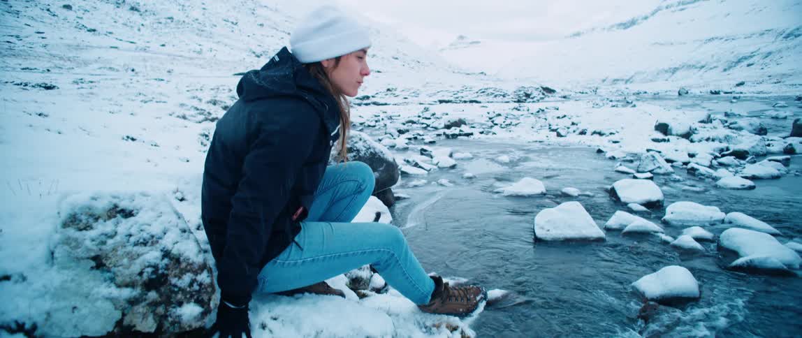 A woman sits by the stream on the mountain