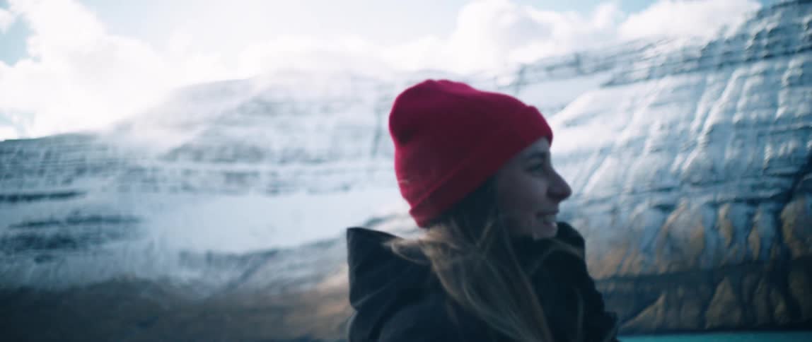 Smiling woman next to a lake surrounded by snowcovered mountain ranges