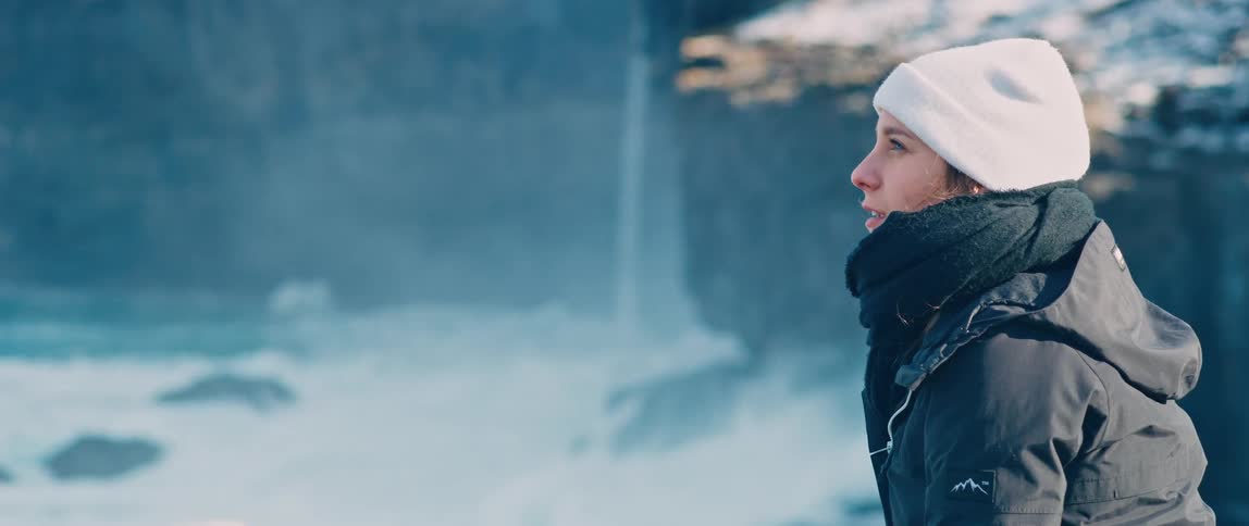 A young woman looks out at the ocean while standing on an overlook