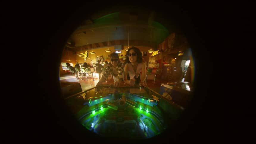 Two people play light up pinball arcade game