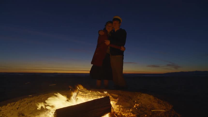 Couple embracing by a campfire in the early evening
