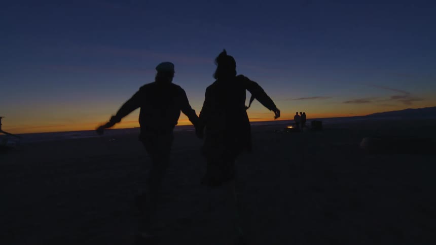 A couple running hand in hand on the beach