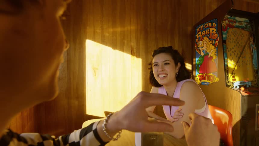 A woman smiles as she listens to her date talk and express himself with his hands in a diner