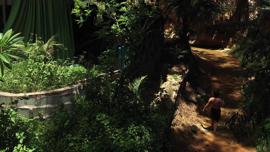 A boy is walking along the river in the forest on a hot day