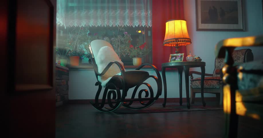 White wooden rocking chair in the center of a room next to a table lamp