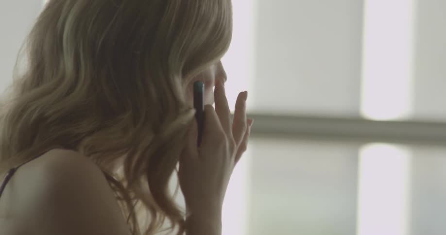 Woman applying makeup while looking in her mirror