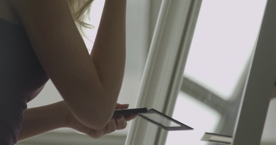 A woman applies makeup while looking in a mirror