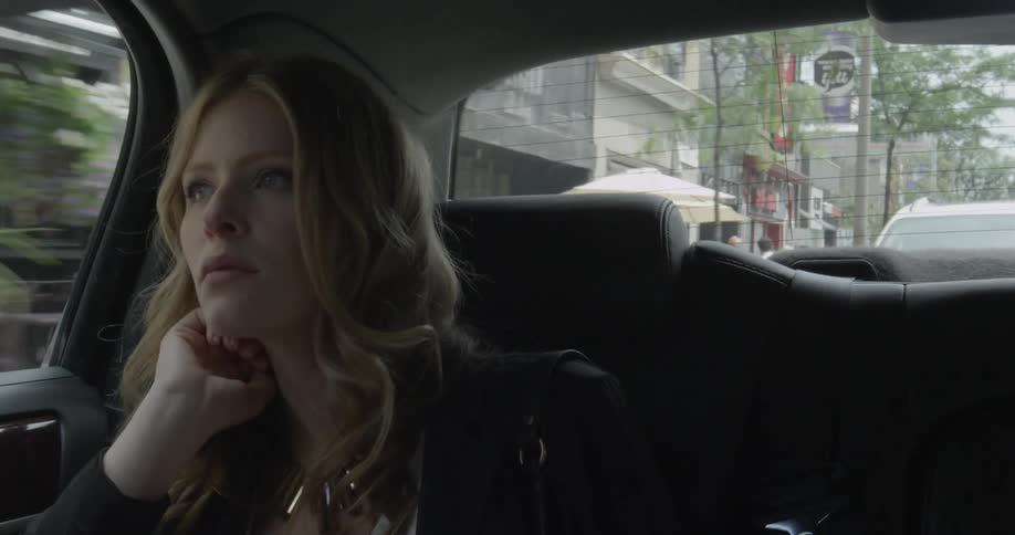 A woman touches her hair while riding in the back of a vehicle