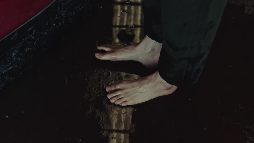 Barefoot woman in a warehouse while it rains