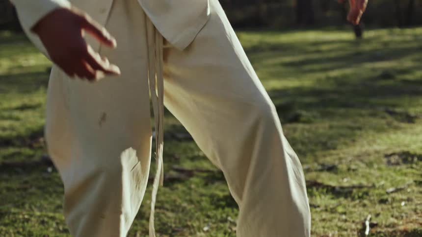 Man wearing a white shirt and pants dances in the green field
