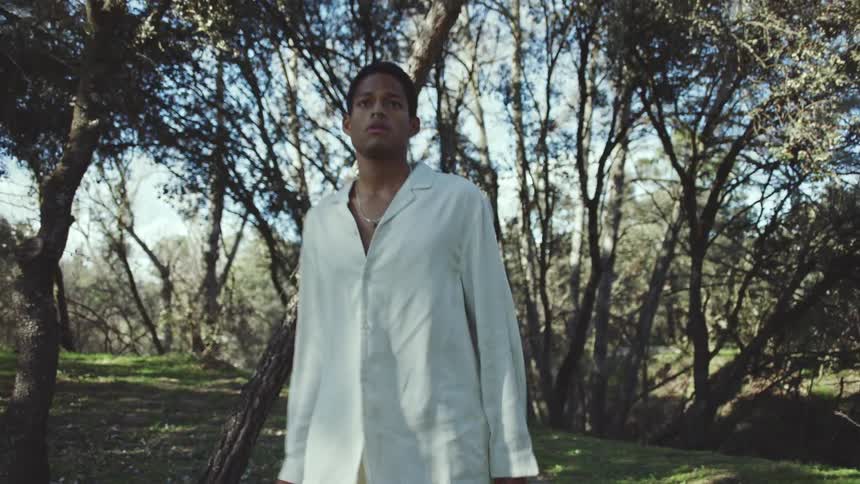 Man walking in the forest wearing a white dress shirt