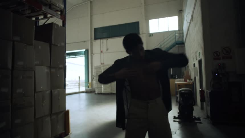 A boy dancing in a warehouse during the day