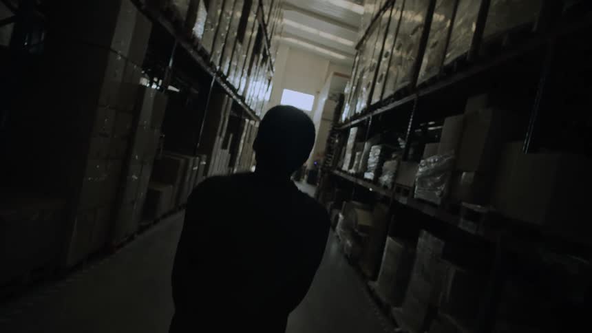 Young man walks in a warehouse corridor