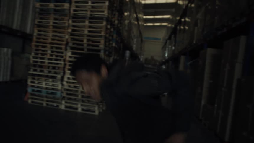Man dances in warehouse aisle near a stack of pallets