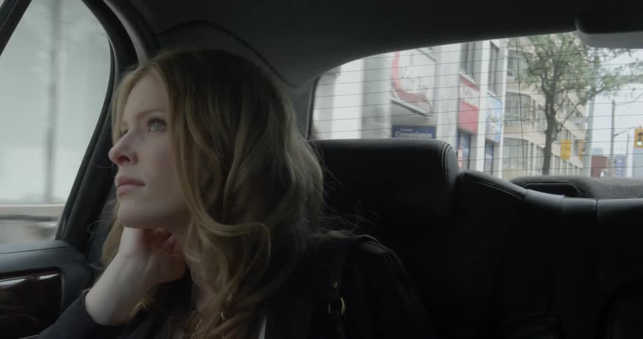 A woman looks out the window as she travels in the back of a car