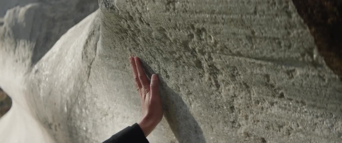 Closeup of a persons hand feeling the texture of a large rock formation