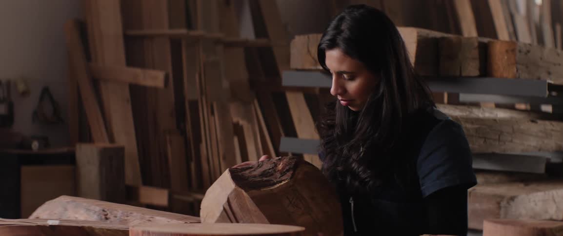 A woman examining pieces of wood in a lumber yard