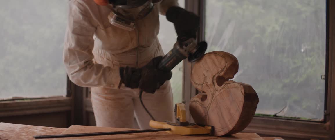 A woman is sculpting a piece of wood with a sander