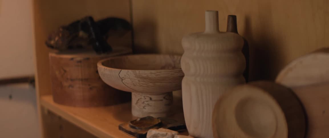 Hand carved wooden items sit on a wooden bookshelf