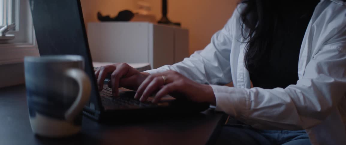 Closeup of a womans hands typing on a laptop