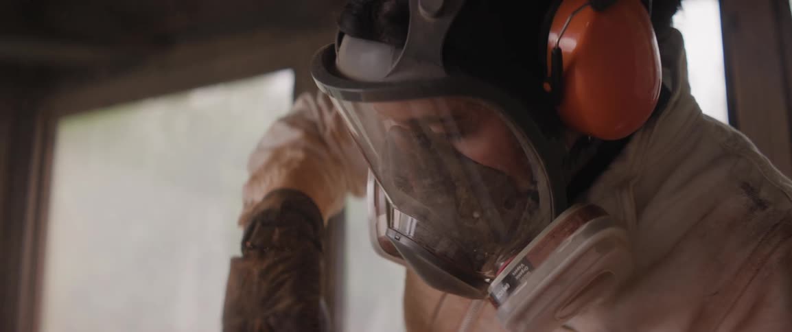 A woman wearing a respirator mask as she uses a grinder on her sculptures