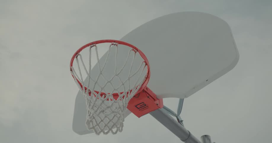 A basketball hoop is shown with an overcast sky behind it