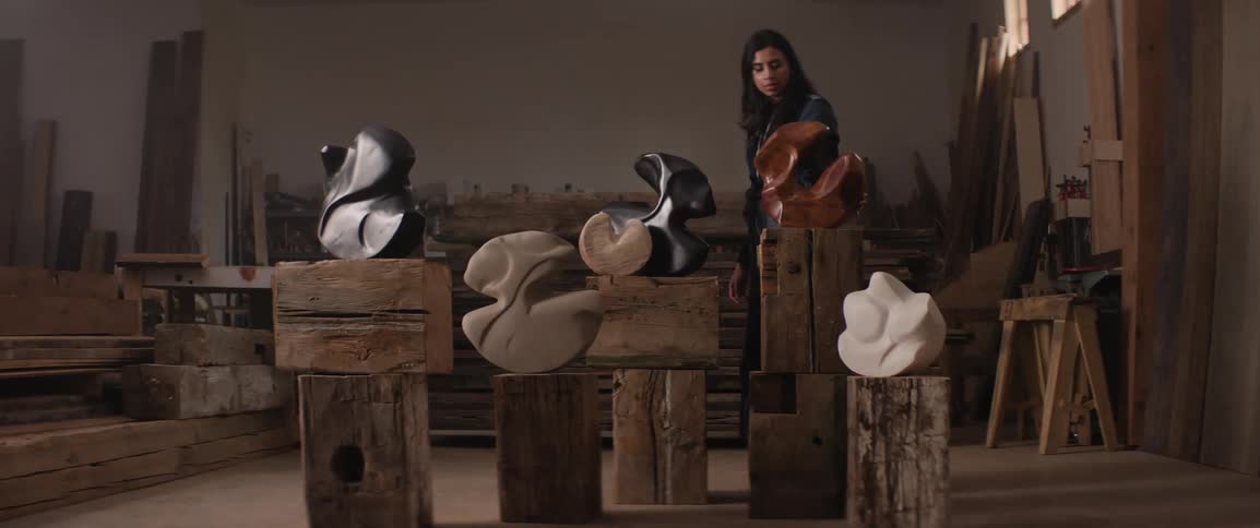 A woman touches one of her wood sculptures