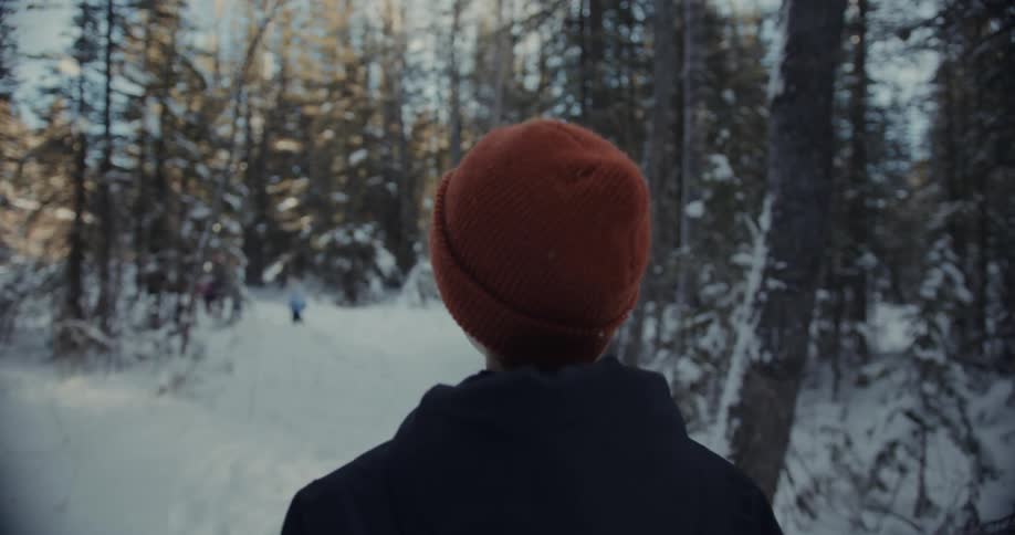 Kid in a cap walking amidst snow in the forest