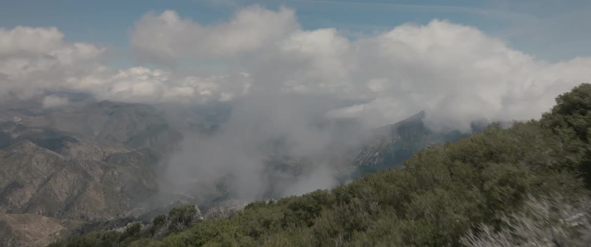Aerial of forest covered mountain range on a partly cloudy winter day