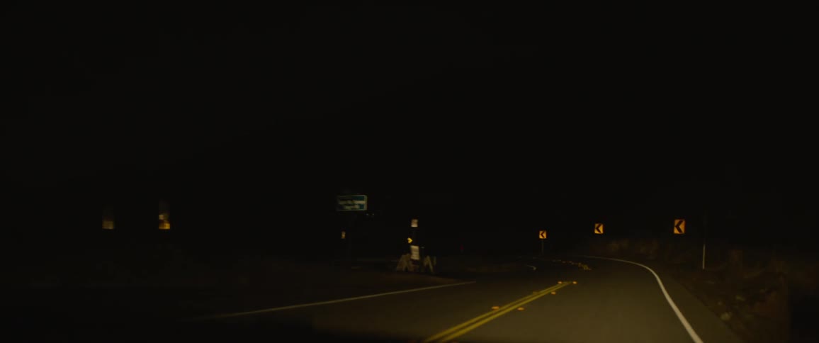 Vehicle headlights illuminate highway during road trip at night