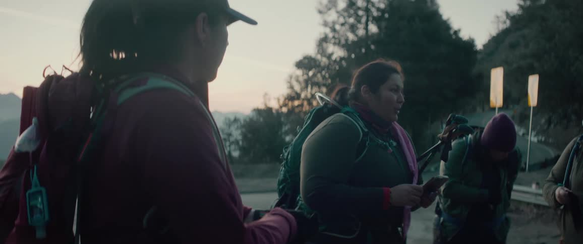 Small group of people gather wearing backpacks planning expedition