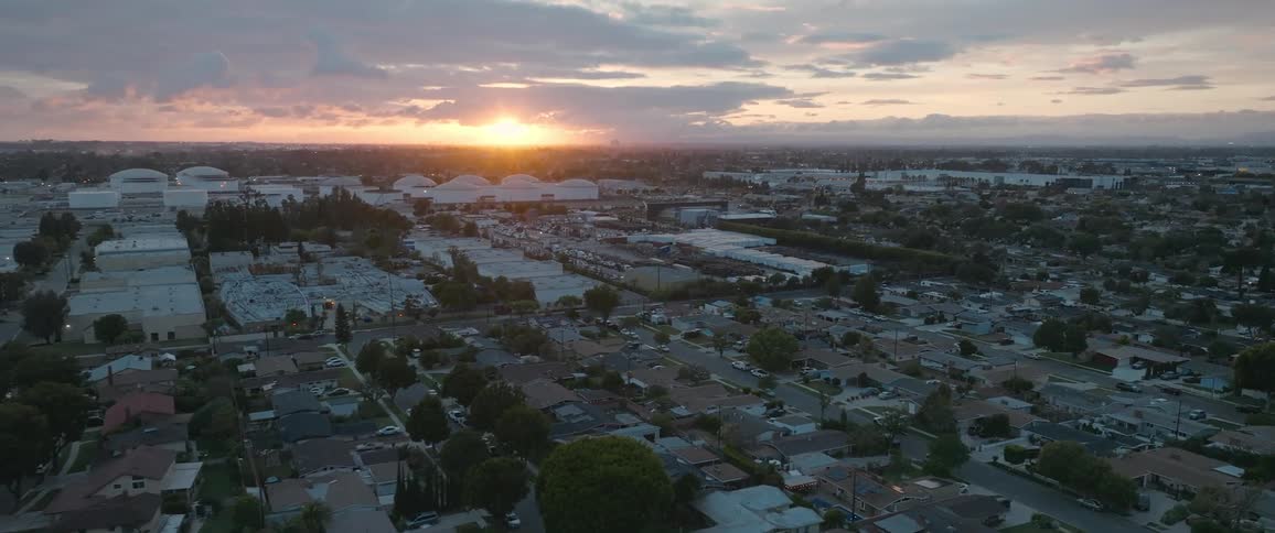 Aerial view of neighborhood rooftops and trees at sunrise sunset