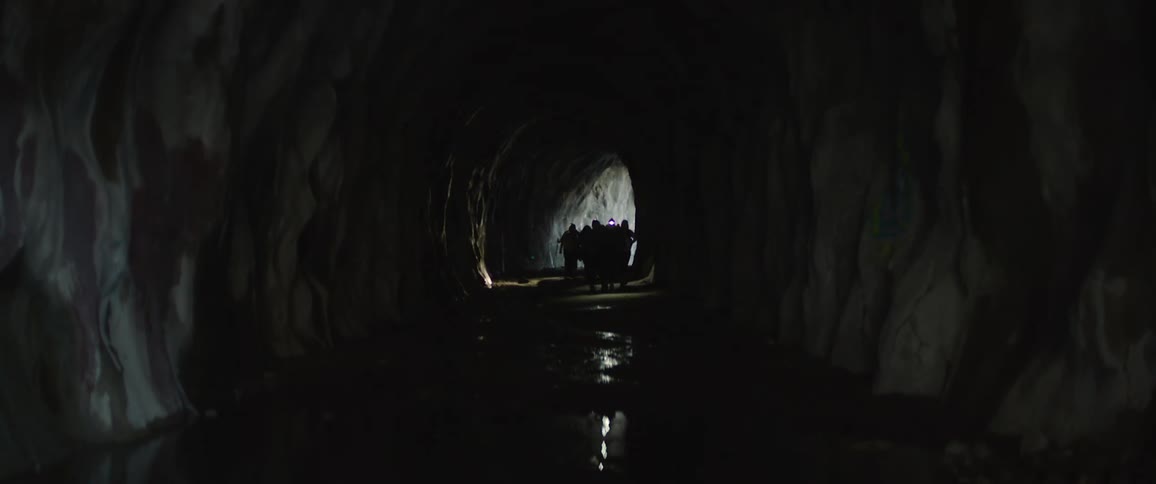 Silhouette of a group of people with lanterns walking inside a cave