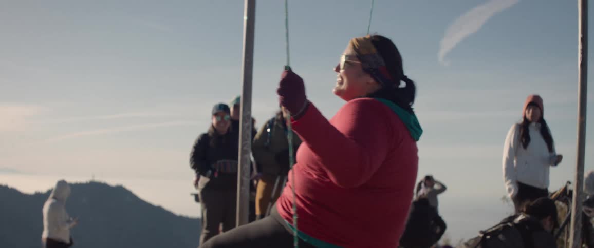 Woman swings over rocky terrain near a small group of people