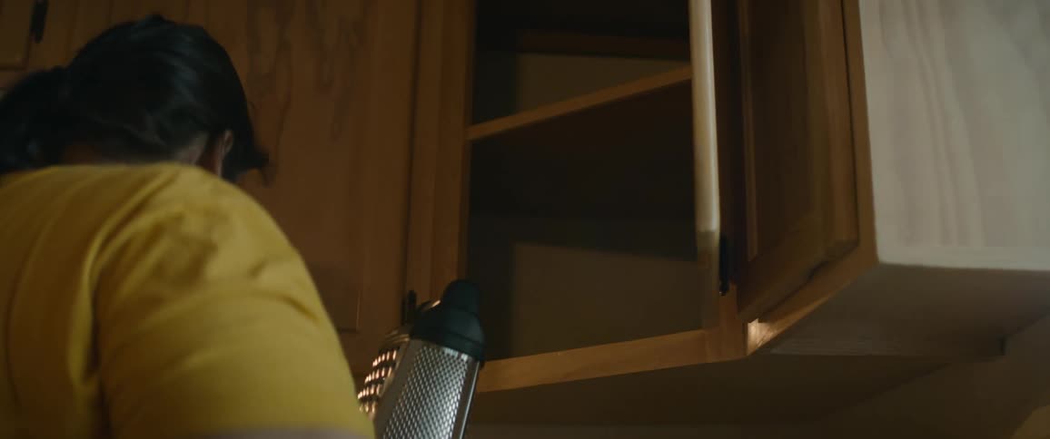 Woman standing in kitchen pulls cheese grater from the cabinet