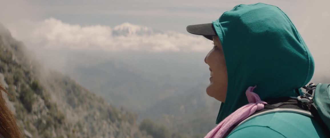 Portrait of a woman with a hood smiling in the midst of a mountain landscape