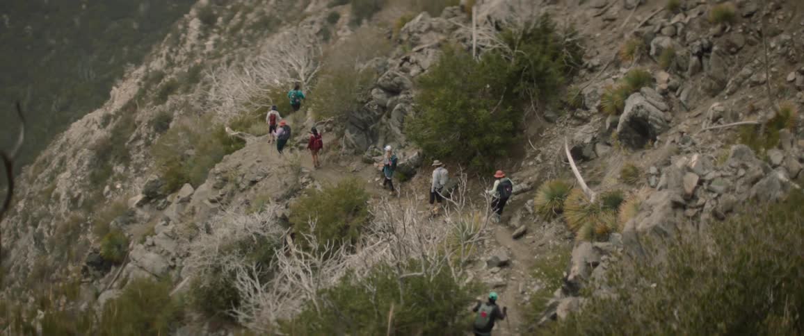 Small group of people hike through rocky terrain during the day