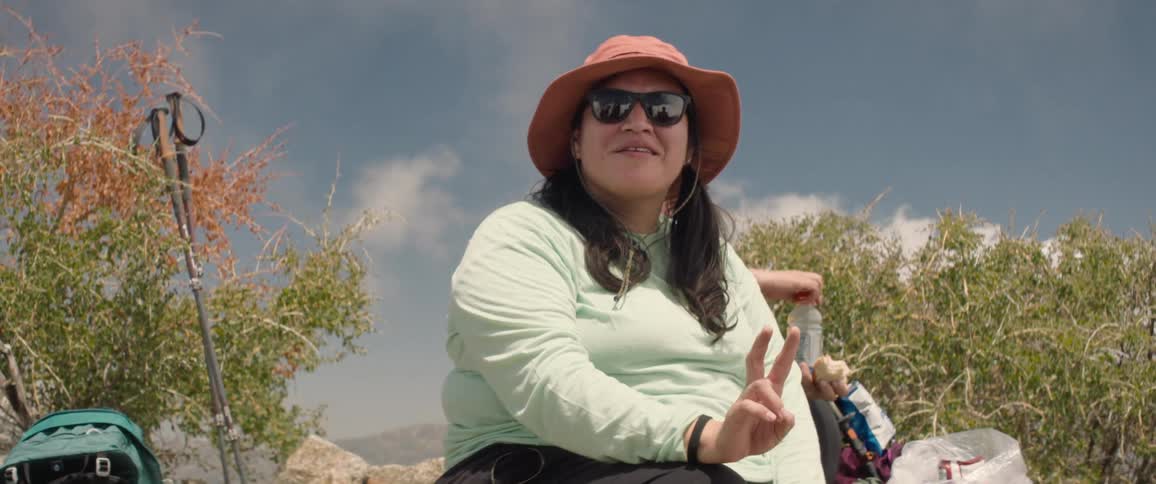 Female hiker talks during a break as another hiker eats