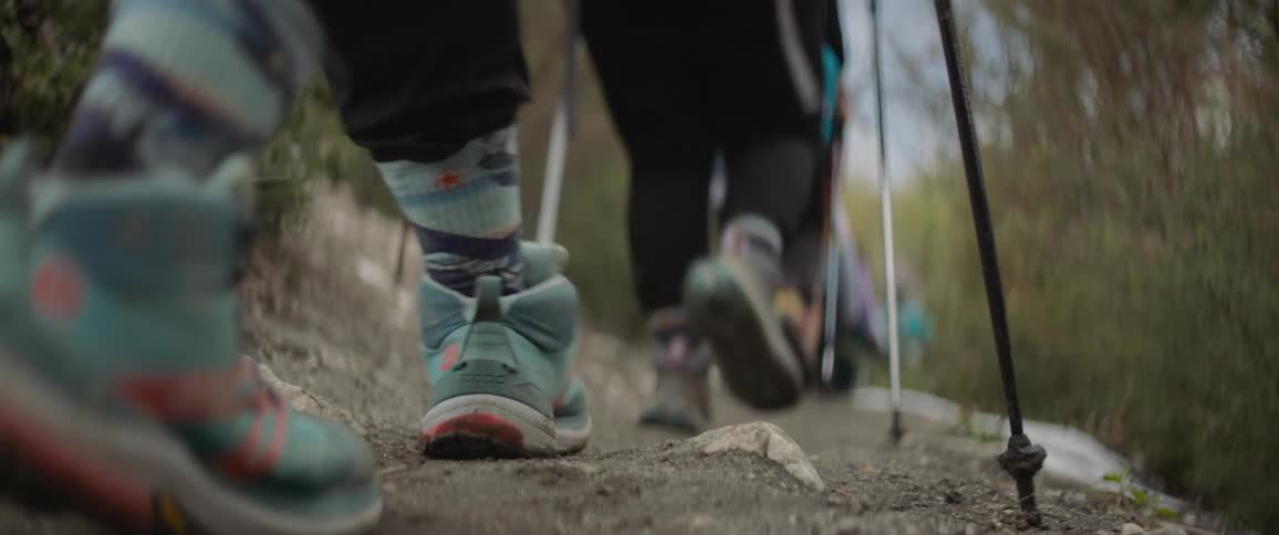 The feet and legs of hikers walking on a narrow trail