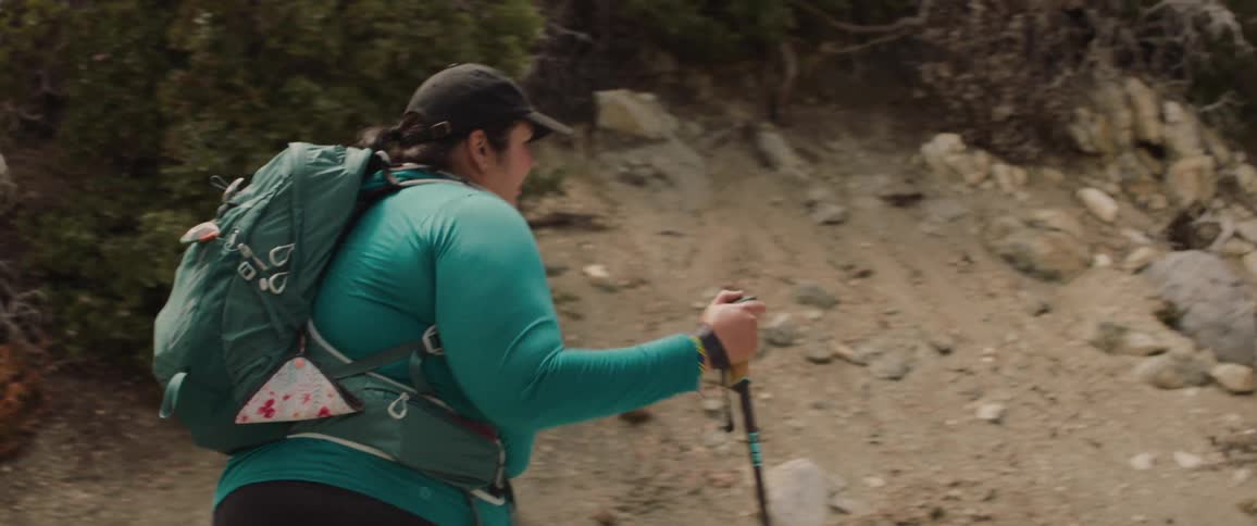 Small group of people hike up rocky landscape with trekking poles