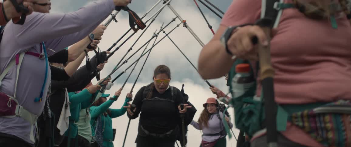 People passing through a humanmade corridor formed by hikers with poles