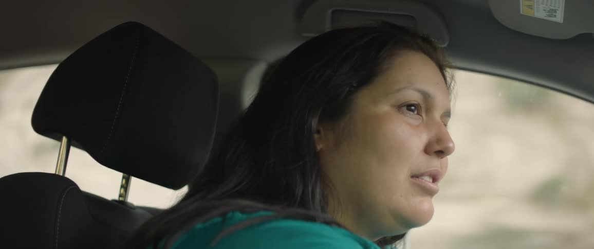 Woman drives car past slope during a road trip