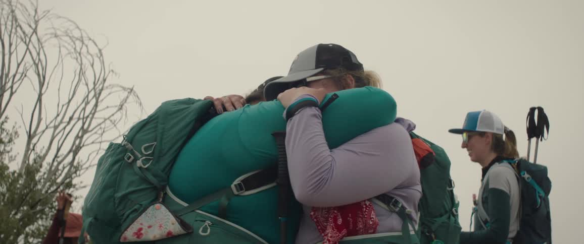 Two friends hugging amid a trail on a cloudy day