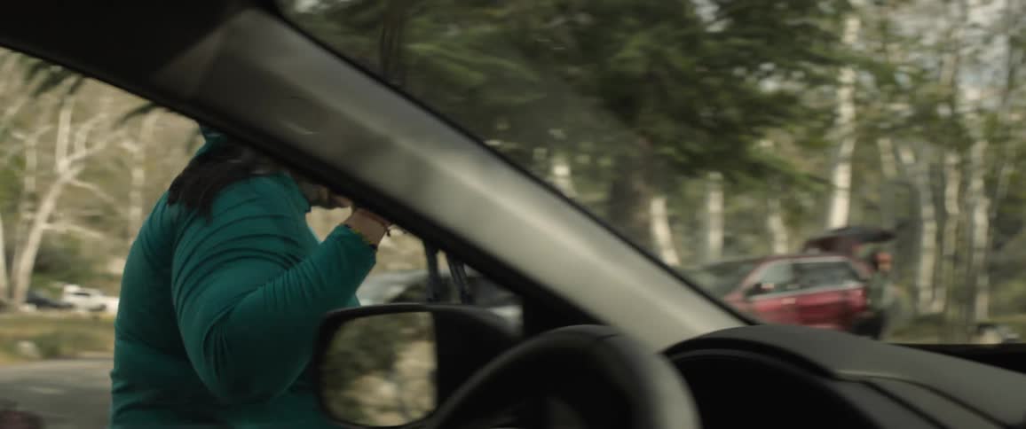 A woman smiles and waves as she exits her parked vehicle